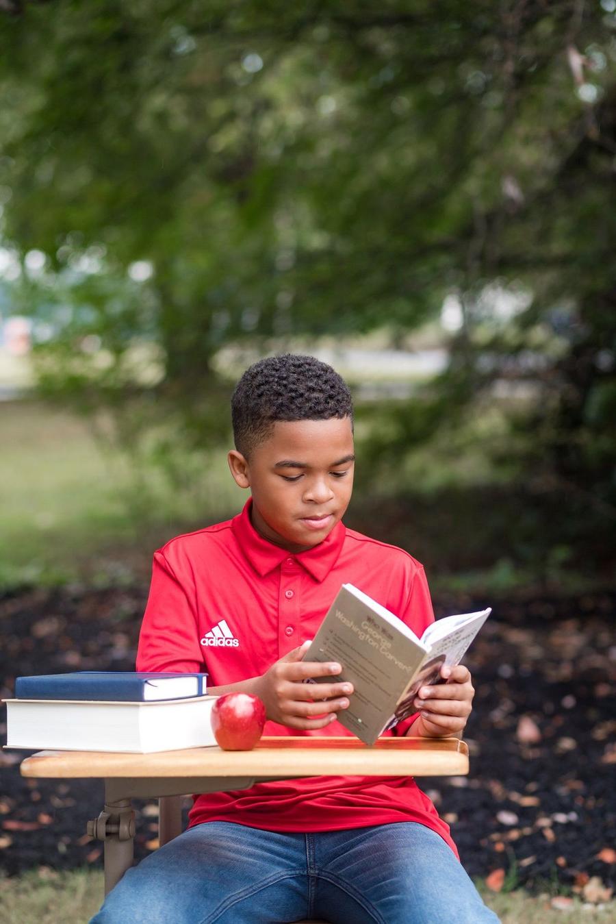 Young Laureates scholar reading outside